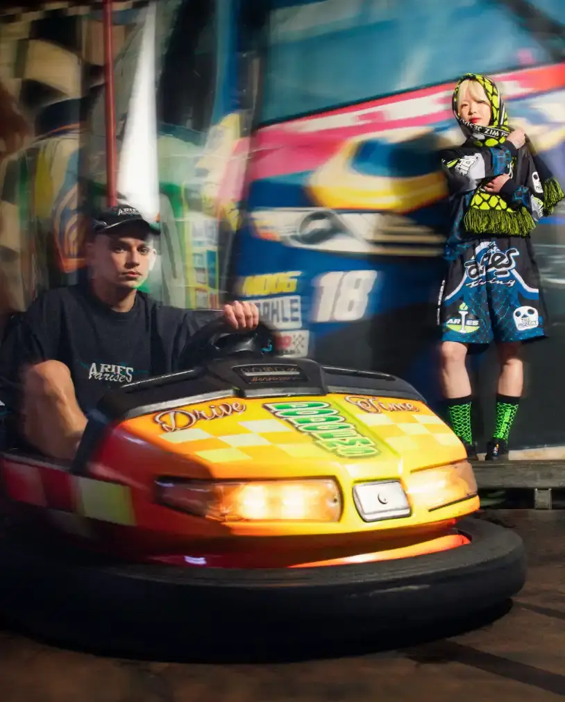 END. AND ARIES LAUNCH ARCADE-INSPIRED COLLECTION image of the launch of a collaborative fashion collection between retailer END. and streetwear brand Aries. The nine-piece "Arcade" collection draws inspiration from 1990s arcade games and motorsports culture, featuring items like graphic t-shirts, shorts, accessories, and caps with racing-themed designs. The piece includes details about pricing (£35-£170), availability through END.'s online store and physical locations, and the campaign photography shot in an actual arcade setting. The collaboration marks part of END.'s 20th anniversary and represents Aries' first partnership with the retailer.