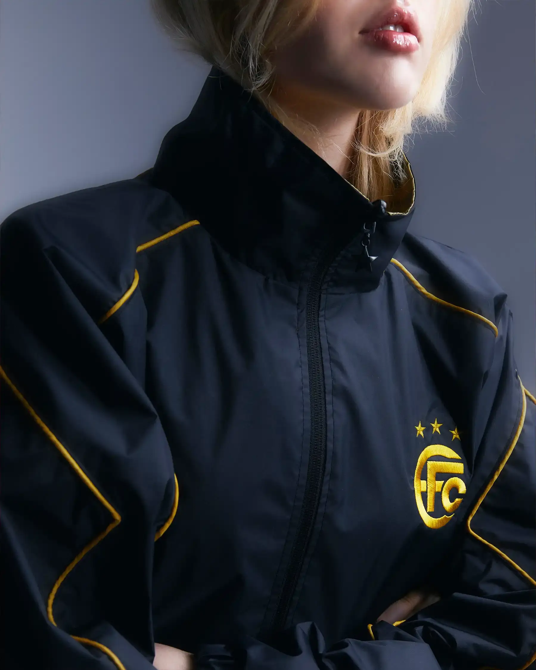 Equipo FC Image shows Equipo FC's reversible "Winners Tracksuit" displayed from both sides - one completely gold and one black with gold details. The tracksuit features star patterns and an embroidered crest, inspired by iconic 2000s football team apparel. (image 4 of 7)
