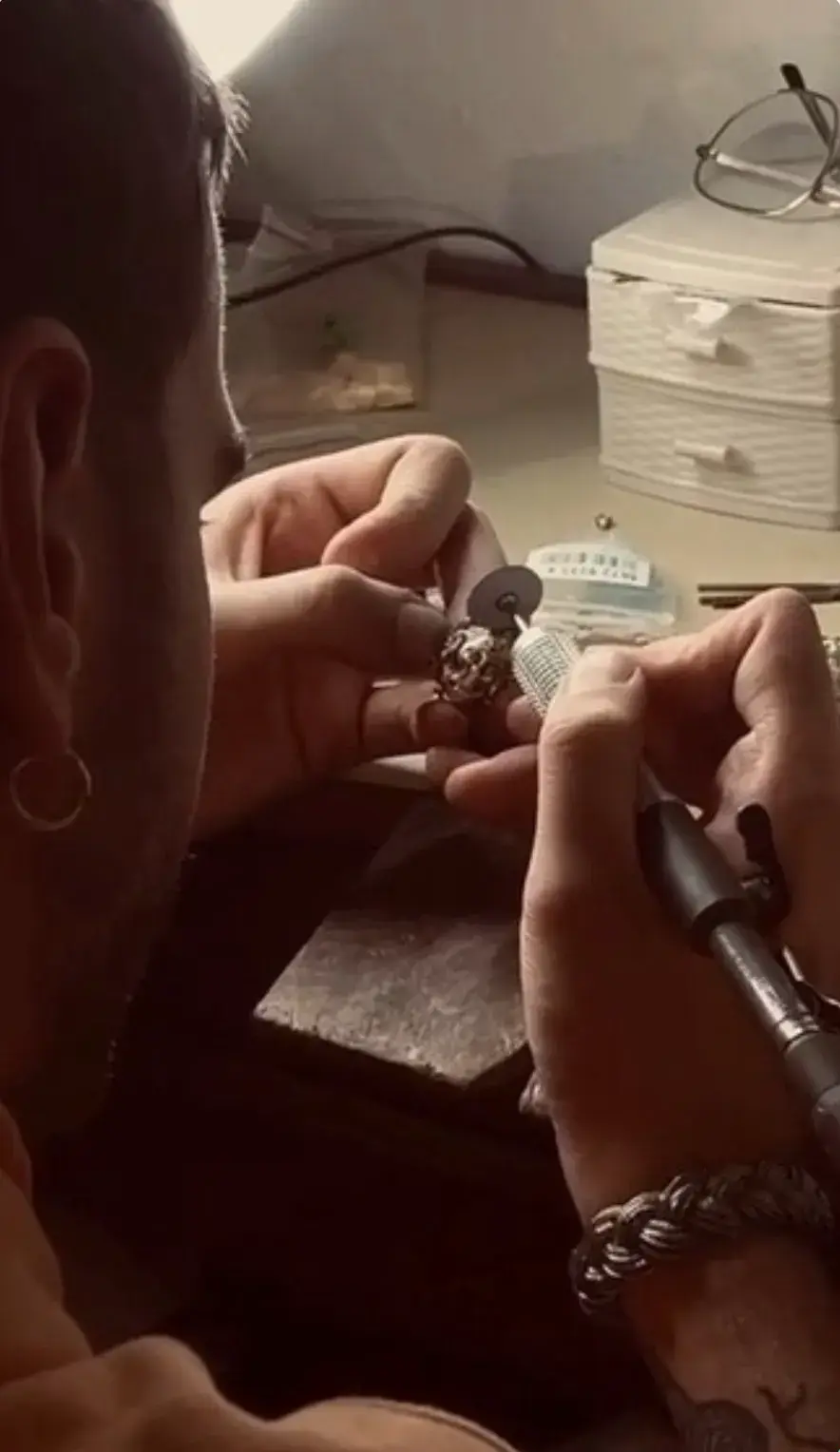 FILIPPO VARLESE: NAPLES' MASTER JEWELLER image of the artisanal philosophy of Neapolitan jeweller and craftsman Filippo Varlese. Raised and educated in Naples—with formal studies at Vanvitelli University and the Tarì Design School, alongside practical training in the historical Borgo Orefici quarter—Varlese views jewelry not merely as precious metal, but as a medium for personal memory and storytelling. The piece details his childhood creative origins, his view of tools and physical scars as a reflective diary of his work, and his creative process when collaborating with clients. It highlights his high-profile custom pieces created for prominent musical artists, including Geolier, Drake, Sayf, and Kid Yugi—focusing on a bespoke "Genius of Evil" pendant and handcrafted Yu-Gi-Oh!-themed display box designed for Kid Yugi. Throughout the interview, Varlese reflects on the artistic solitude of his workshop, the influence of his late mentor Alfredo, and his dedication to authenticity over commercial fame. (image 4 of 6)