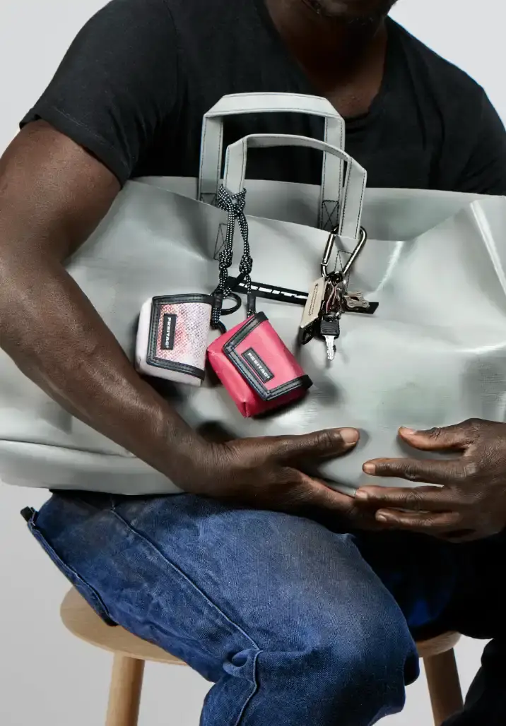 FREITAG TRANSFORMS PRODUCTION WASTE INTO BAG CHARMS image about FREITAG's new Lucky Trucking Charms collection, which repurposes production waste from truck tarps into bag accessories and keychains.