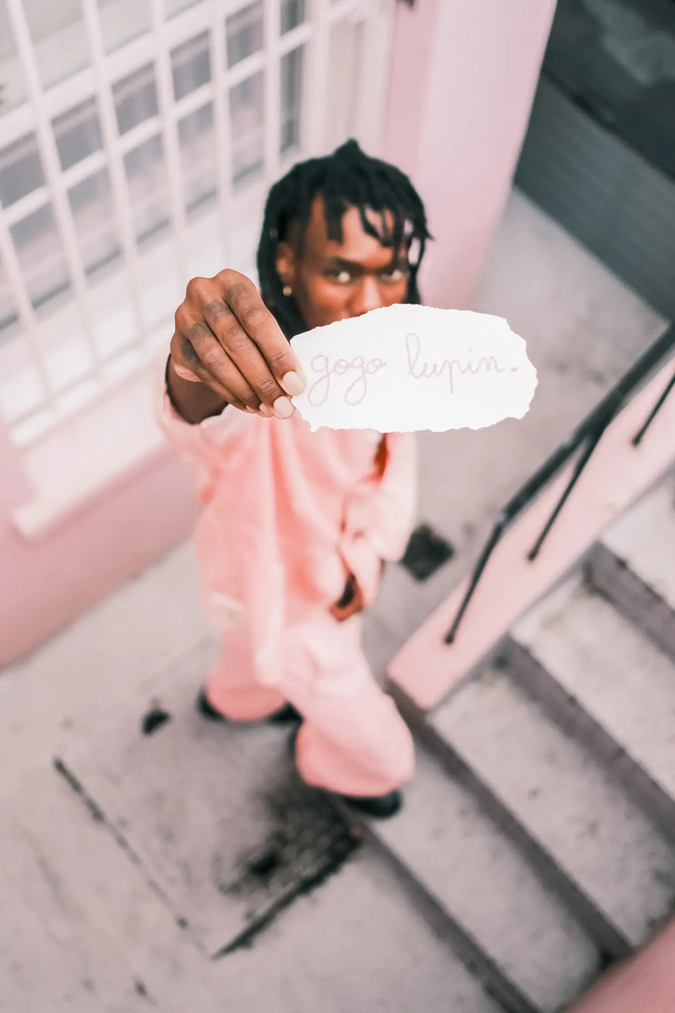 image of multidisciplinary artist Gogo Lupin posing in a pink-accented outfit during a portrait session for his Casawi interview. (image 2 of 2)