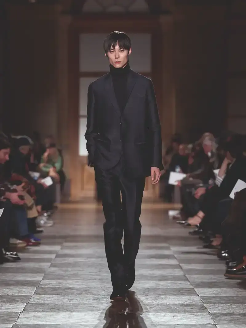 HERMÈS MENSWEAR FW26 COLLECTION Article about Hermès Fall Winter 2026 menswear collection designed by Véronique Nichanian. The collection emphasizes clean construction, quality fabrics, and interior garment finishing. Color palette ranges from hemp and lichen to saffron and midnight blue. The design philosophy focuses on timeless pieces and precise craftsmanship. (image 54 of 58)