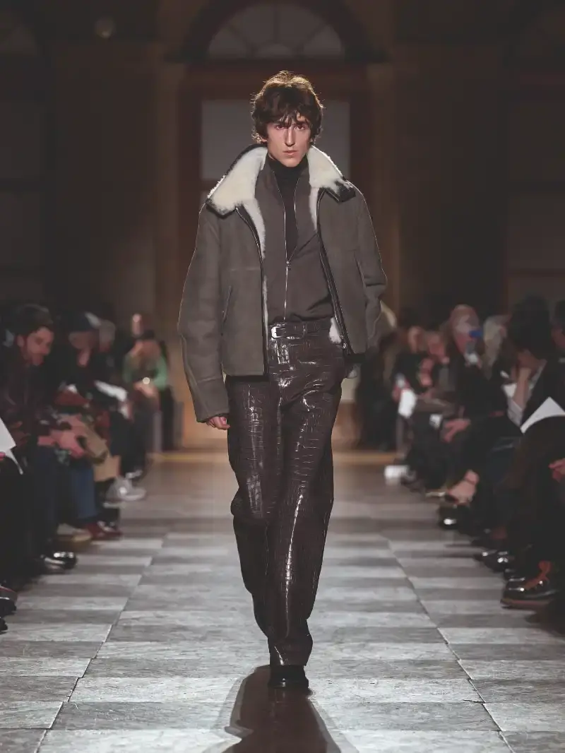 HERMÈS MENSWEAR FW26 COLLECTION Article about Hermès Fall Winter 2026 menswear collection designed by Véronique Nichanian. The collection emphasizes clean construction, quality fabrics, and interior garment finishing. Color palette ranges from hemp and lichen to saffron and midnight blue. The design philosophy focuses on timeless pieces and precise craftsmanship. (image 15 of 58)