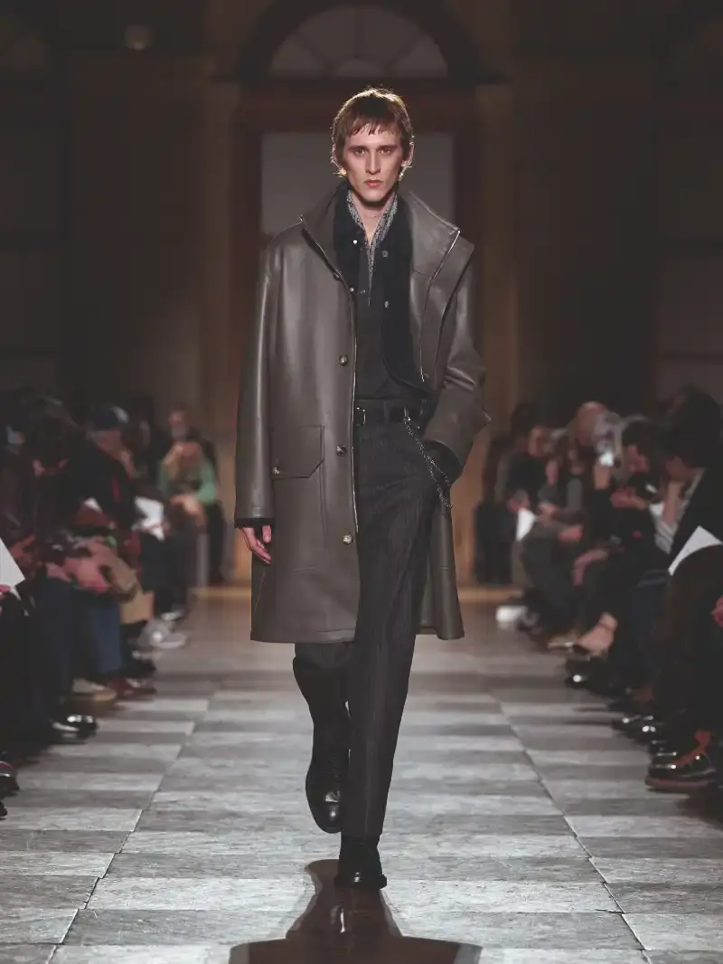 HERMÈS MENSWEAR FW26 COLLECTION Article about Hermès Fall Winter 2026 menswear collection designed by Véronique Nichanian. The collection emphasizes clean construction, quality fabrics, and interior garment finishing. Color palette ranges from hemp and lichen to saffron and midnight blue. The design philosophy focuses on timeless pieces and precise craftsmanship. (image 12 of 58)