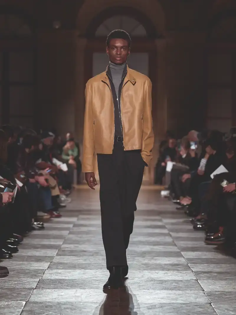 HERMÈS MENSWEAR FW26 COLLECTION Article about Hermès Fall Winter 2026 menswear collection designed by Véronique Nichanian. The collection emphasizes clean construction, quality fabrics, and interior garment finishing. Color palette ranges from hemp and lichen to saffron and midnight blue. The design philosophy focuses on timeless pieces and precise craftsmanship. (image 32 of 58)