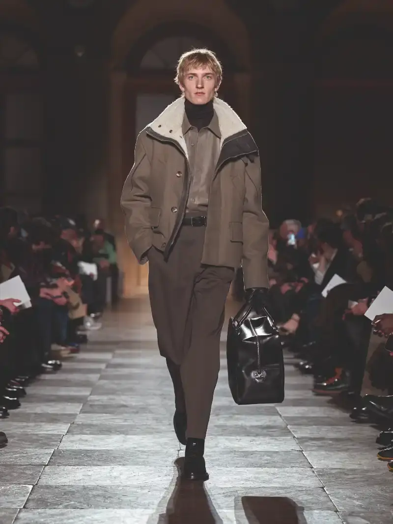 HERMÈS MENSWEAR FW26 COLLECTION Article about Hermès Fall Winter 2026 menswear collection designed by Véronique Nichanian. The collection emphasizes clean construction, quality fabrics, and interior garment finishing. Color palette ranges from hemp and lichen to saffron and midnight blue. The design philosophy focuses on timeless pieces and precise craftsmanship. (image 3 of 58)