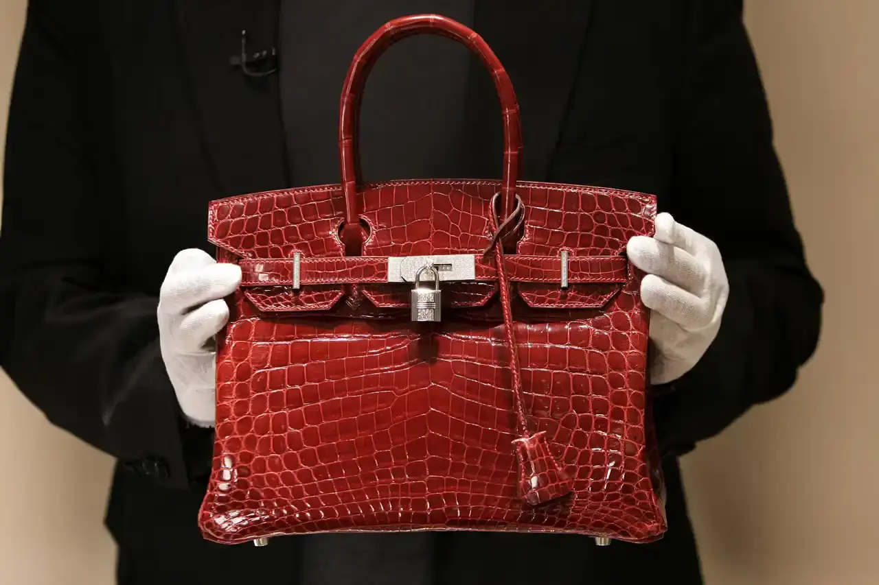 This article reports on luxury fashion brand Hermès' plans to raise prices on all US products beginning May 1, 2025, in response to new tariffs implemented by President Trump. The piece covers Hermès' recent financial performance, noting Q1 sales growth of 7.2% (below analysts' expectations), and contextualizes the price hikes within broader luxury market challenges including post-pandemic spending fatigue, inflation, and economic issues in China. The article also mentions that Hermès recently became the world's most valuable luxury company, surpassing LVMH.