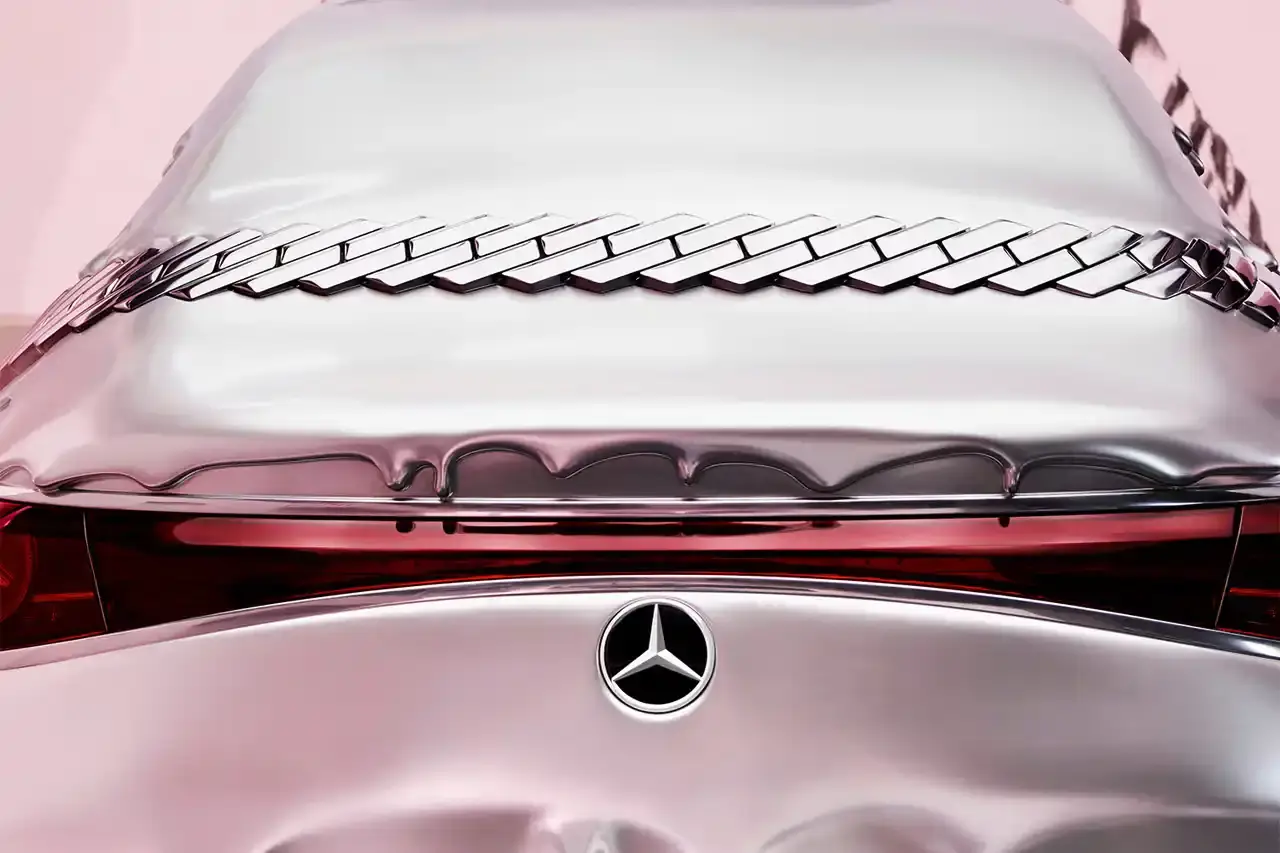 CLA GETS ROYAL CHROME TREATMENT IN ICE SPICE'S MERCEDES COLLAB image of rapper Ice Spice's custom collaboration with Mercedes-Benz, featuring a chrome-finished CLA model with princess-themed detailing. It explains that this is part of Mercedes' "Class of Creators" initiative, where five artists will create custom interpretations of the CLA. The piece details the unveiling event at Mercedes' New York dealership, which included performances from Broadway's "Hell's Kitchen" cast and music by DJ LPX. The article also mentions Ice Spice's upcoming merchandise collection and notes that other collaborators will include Gustaf Westman, KidSuper, League of Legends, and Hot Wheels. (image 8 of 11)