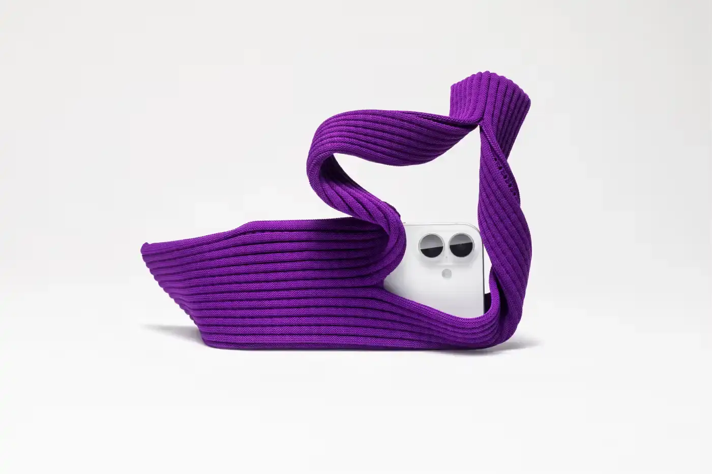 ISSEY MIYAKE AND APPLE LAUNCH IPHONE POCKET A 3D-knitted textile iPhone holder in a rectangular shape with ribbed pleated structure, available with short wrist strap or long crossbody strap in multiple colors, designed by Issey Miyake and Apple. (image 6 of 12)