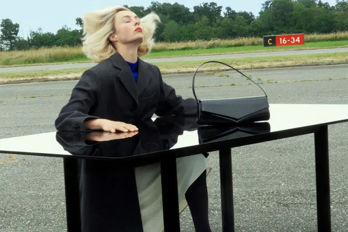 image of the Jil Sander Fall Winter 2026 campaign featuring models on an airport runway with foil and latex props.