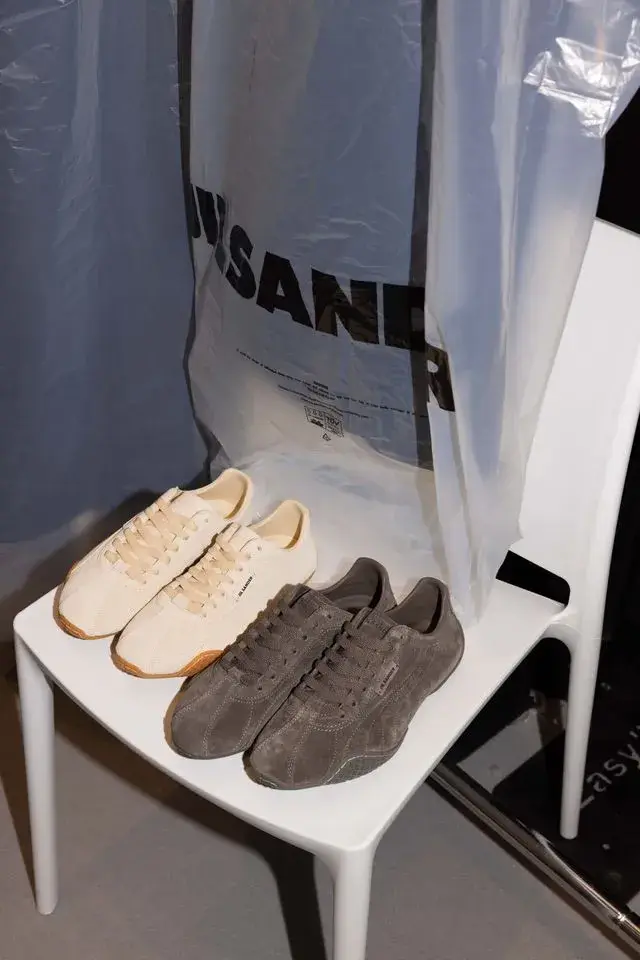 JIL SANDER AND PUMA PRESENT NEW H STREET SNEAKERS Studio image of Jil Sander and Puma low profile leather sneaker in ivory and dark brown with a thin rubber sole and minimal branding.