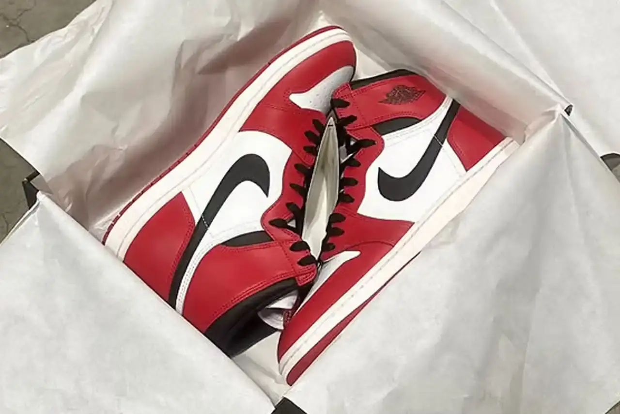 Air Jordan 1 Hi '85 "Chicago" sneaker featuring white leather upper with red overlays, black Swoosh logo, and higher collar height characteristic of the '85 model.
