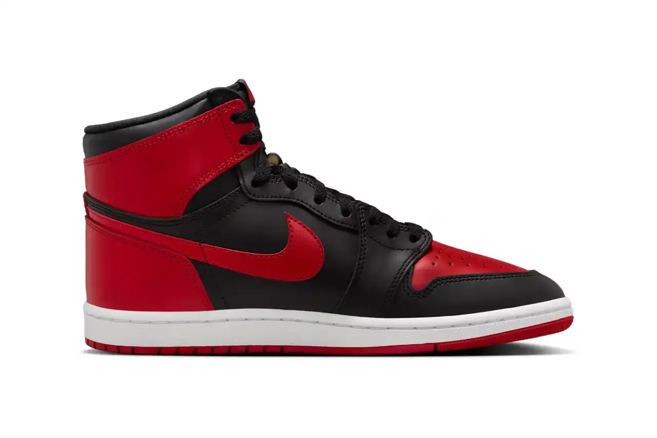 Nike Air Jordan 1 Hi '85 'Bred' sneaker in black and red leather with white midsole. Features original 1985 specifications including modified Swoosh shape, compact Wings logo, and elevated collar height. The shoe has a black leather base with red leather overlays, white Nike Swoosh, and red rubber outsole. (image 2 of 7)