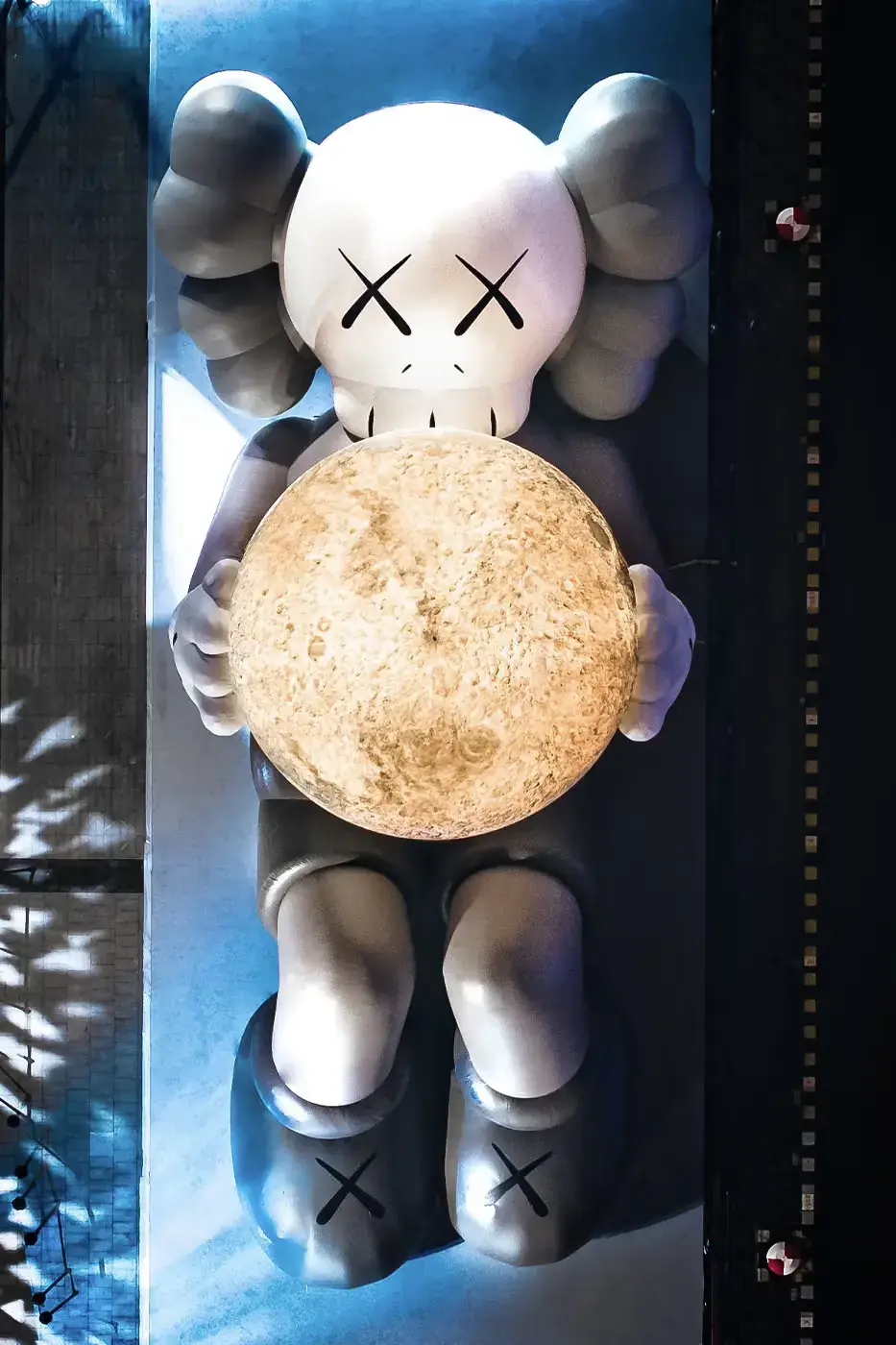 KAWS:HOLIDAY Shanghai installation featuring COMPANION holding glowing moon at North Bund, with details on limited edition vinyl figures and merchandise (image 3 of 4)