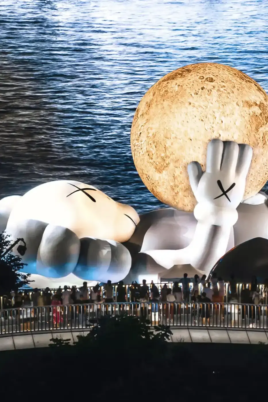 KAWS:HOLIDAY Shanghai installation featuring COMPANION holding glowing moon at North Bund, with details on limited edition vinyl figures and merchandise