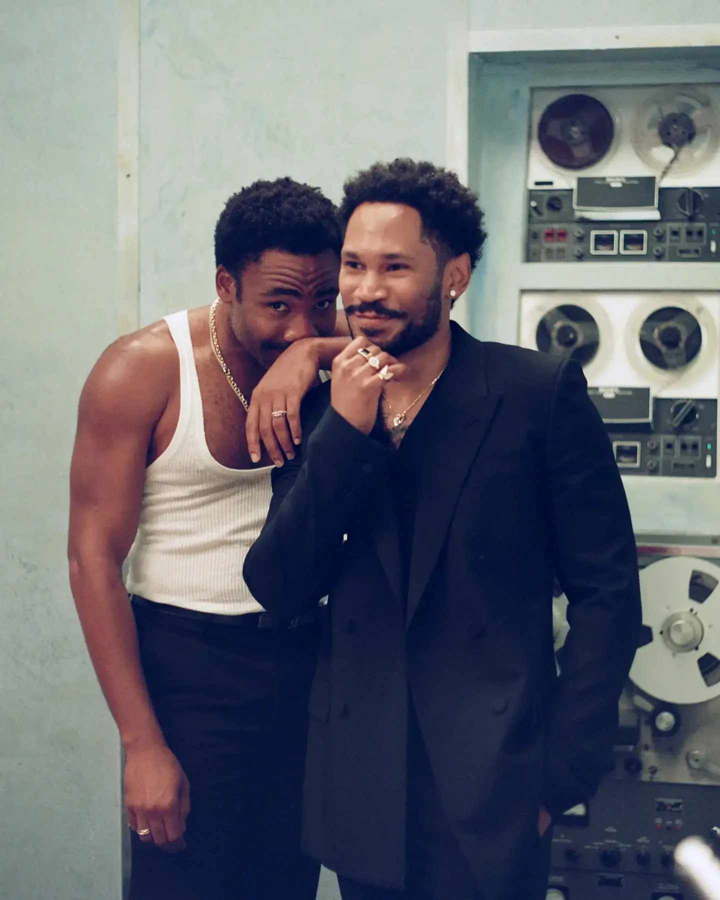 KAYTRANADA and Childish Gambino approach a dimly lit recording studio entrance wearing custom-fitted Gucci suits