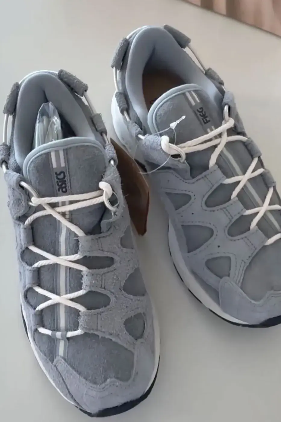 KITH, GIORGIO ARMANI AND ASICS REVEAL THE GEL-MAI 0.1 image about the KITH, Giorgio Armani and ASICS GEL-Mai 0.1, a grey shaggy suede sneaker with navy GEL units and no confirmed release date or price.