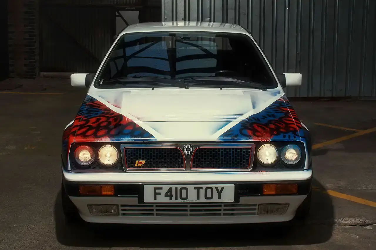 Spot A Lancia Delta Integrale rally car painted by artist Slawn, featuring bold artistic interpretations of the classic Martini racing livery with contemporary street art elements. (image 5 of 13)