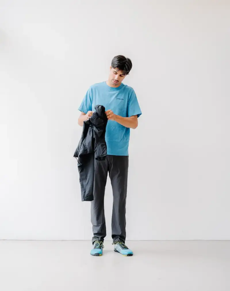 HOW SHAI DATAUKER REDEFINES CLOTHING, IDENTITY, AND DAILY LIFE Shai Datauker wearing his daily uniform-a bright red Adidas tracksuit and white t-shirt-sitting in a minimalist interior during an interview about fashion and identity. (image 4 of 7)
