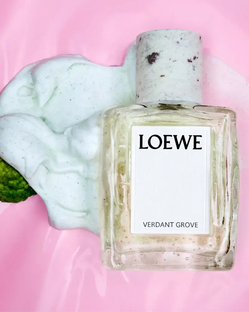 LOEWE PERFUMES EXPANDS CRAFTED COLLECTION Image series showing still-life perfume bottles with granite caps alongside raw botanical ingredients, pigment powders, and fresh citrus slices.
