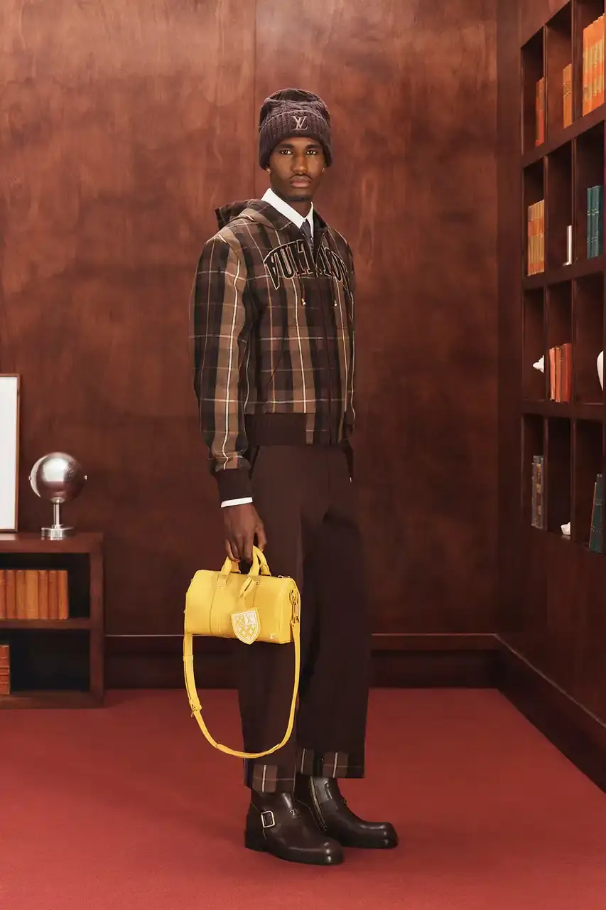 LOUIS VUITTON FALL 2026 MENSWEAR PREVIEW image about Louis Vuitton's upcoming Fall 2026 menswear collection designed by Pharrell Williams. The piece discusses the collection's American collegiate inspiration, key design elements including tartan patterns and heritage stripes, outerwear focus, and September release timeline. Contains detailed descriptions of clothing items, patterns, materials, and accessories without accompanying images. (image 3 of 29)