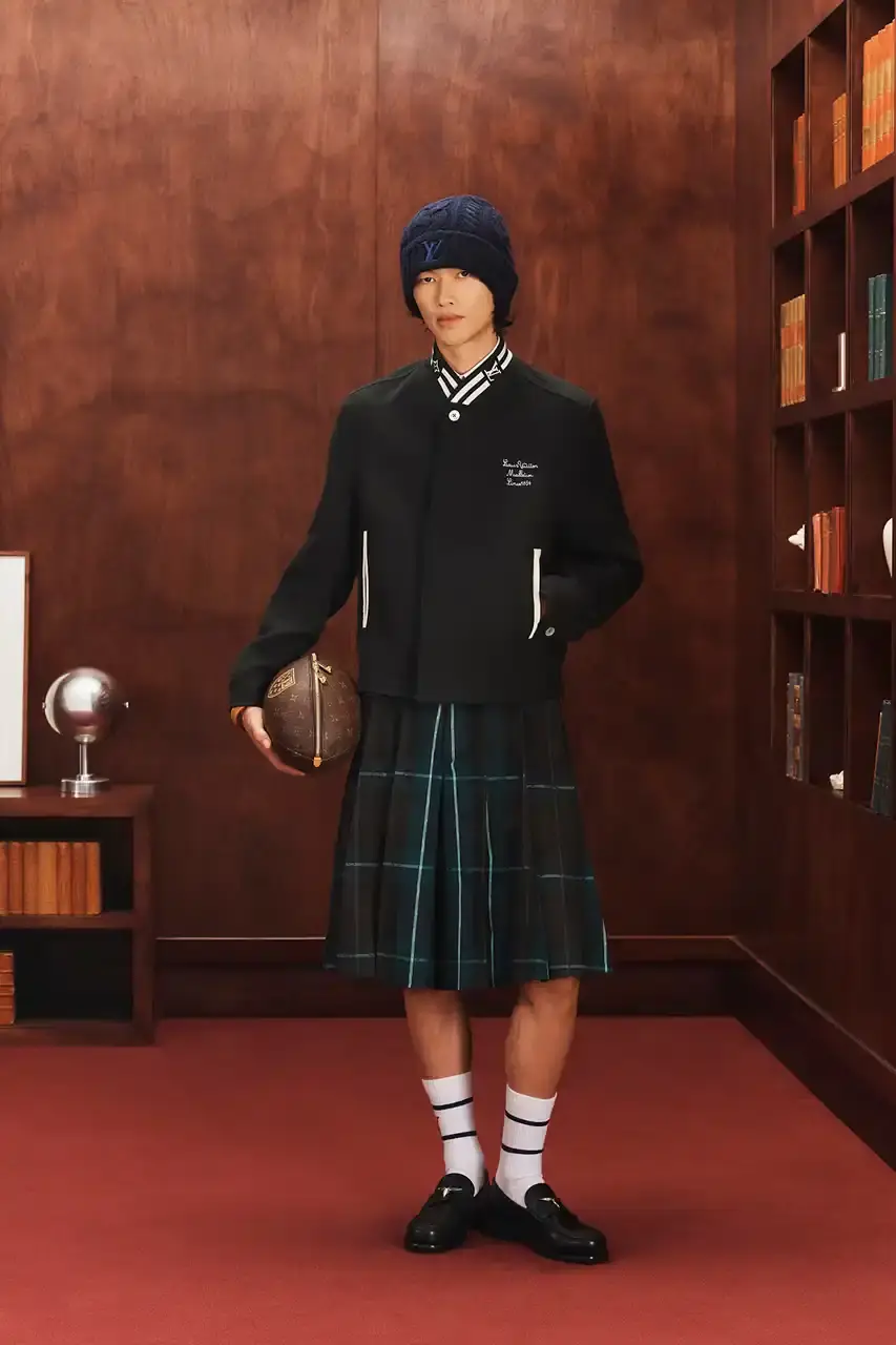 LOUIS VUITTON FALL 2026 MENSWEAR PREVIEW image about Louis Vuitton's upcoming Fall 2026 menswear collection designed by Pharrell Williams. The piece discusses the collection's American collegiate inspiration, key design elements including tartan patterns and heritage stripes, outerwear focus, and September release timeline. Contains detailed descriptions of clothing items, patterns, materials, and accessories without accompanying images. (image 22 of 29)