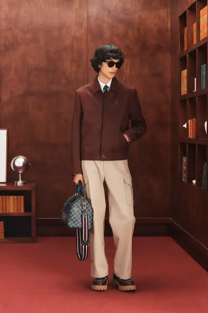 LOUIS VUITTON FALL 2026 MENSWEAR PREVIEW image about Louis Vuitton's upcoming Fall 2026 menswear collection designed by Pharrell Williams. The piece discusses the collection's American collegiate inspiration, key design elements including tartan patterns and heritage stripes, outerwear focus, and September release timeline. Contains detailed descriptions of clothing items, patterns, materials, and accessories without accompanying images. (image 23 of 29)