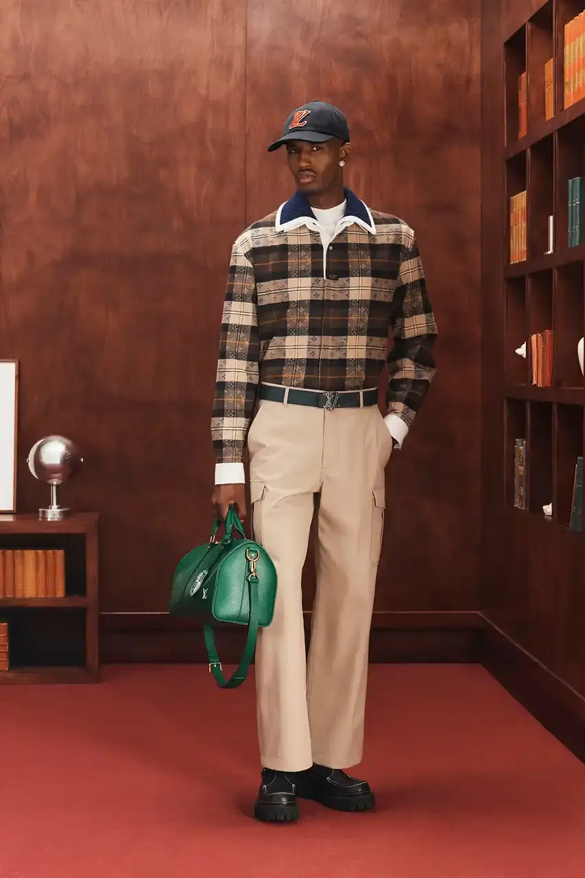 LOUIS VUITTON FALL 2026 MENSWEAR PREVIEW image about Louis Vuitton's upcoming Fall 2026 menswear collection designed by Pharrell Williams. The piece discusses the collection's American collegiate inspiration, key design elements including tartan patterns and heritage stripes, outerwear focus, and September release timeline. Contains detailed descriptions of clothing items, patterns, materials, and accessories without accompanying images. (image 8 of 29)