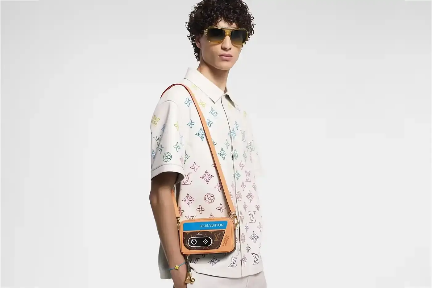 Louis Vuitton Louis Vuitton Spring 2025 accessories collection featuring music technology-inspired luxury items. The image shows an iPod-shaped leather crossbody bag with a display screen showing 'Louis Vuitton Collection Spring 2025' and an LV monogram replacing the scroll wheel. Also visible are a cassette player-styled wallet with embossed control buttons and a cassette tape card holder with 'Side A' and 'Side B' graphics. Gold headphone-shaped zipper pulls complete the nostalgic design. (image 3 of 17)