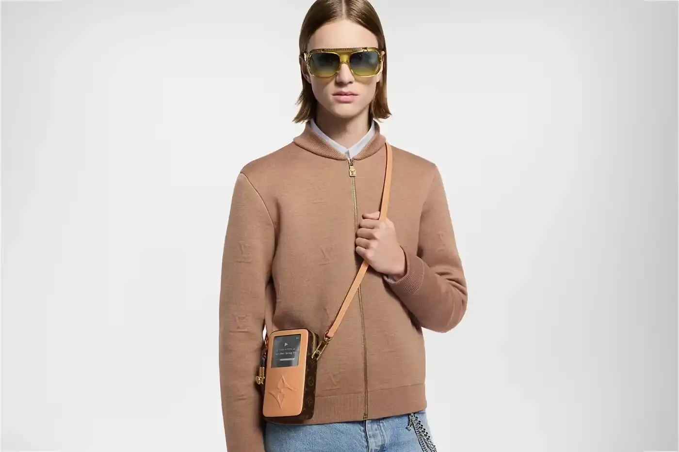 Louis Vuitton Louis Vuitton Spring 2025 accessories collection featuring music technology-inspired luxury items. The image shows an iPod-shaped leather crossbody bag with a display screen showing 'Louis Vuitton Collection Spring 2025' and an LV monogram replacing the scroll wheel. Also visible are a cassette player-styled wallet with embossed control buttons and a cassette tape card holder with 'Side A' and 'Side B' graphics. Gold headphone-shaped zipper pulls complete the nostalgic design.