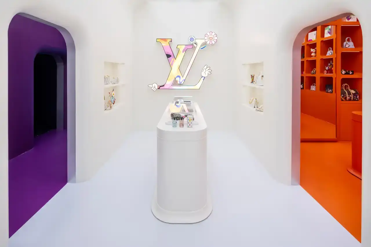 Brad Dickson Louis Vuitton's SoHo boutique exterior features Takashi Murakami's colorful flower motifs and rainbow monogram patterns. The multi-level space includes exhibition areas displaying archival pieces, a downstairs cinema, retail section with new collection items, and a themed café with custom-designed cups. (image 3 of 7)