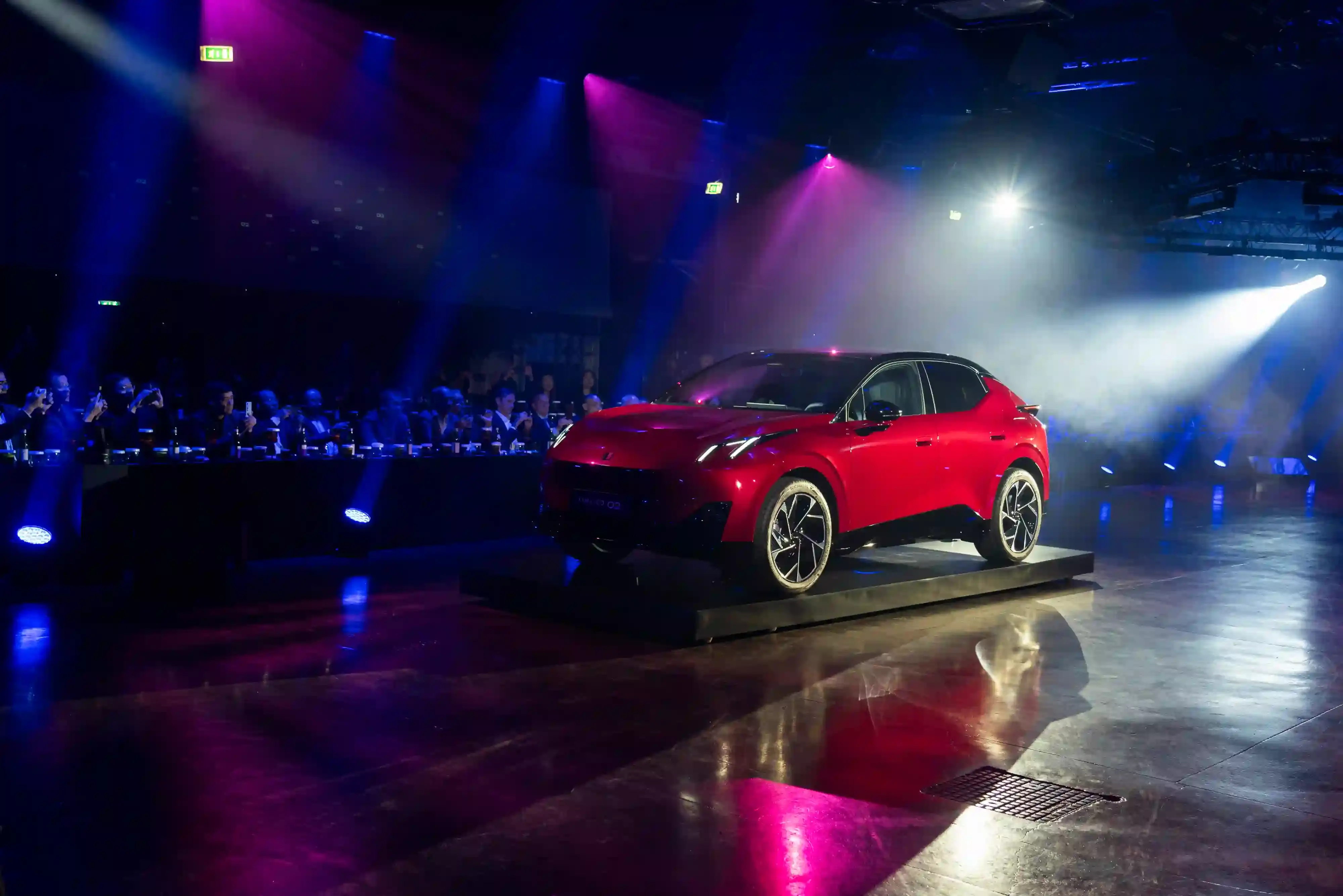 LYNK & CO LAUNCHES 02: FIRST ELECTRIC VEHICLE FOR EUROPEAN MARKET Lynk & Co 02 electric vehicle displayed at Spazio Antologico in Milan, showing the car's front three-quarter view against architectural backdrop (image 2 of 4)
