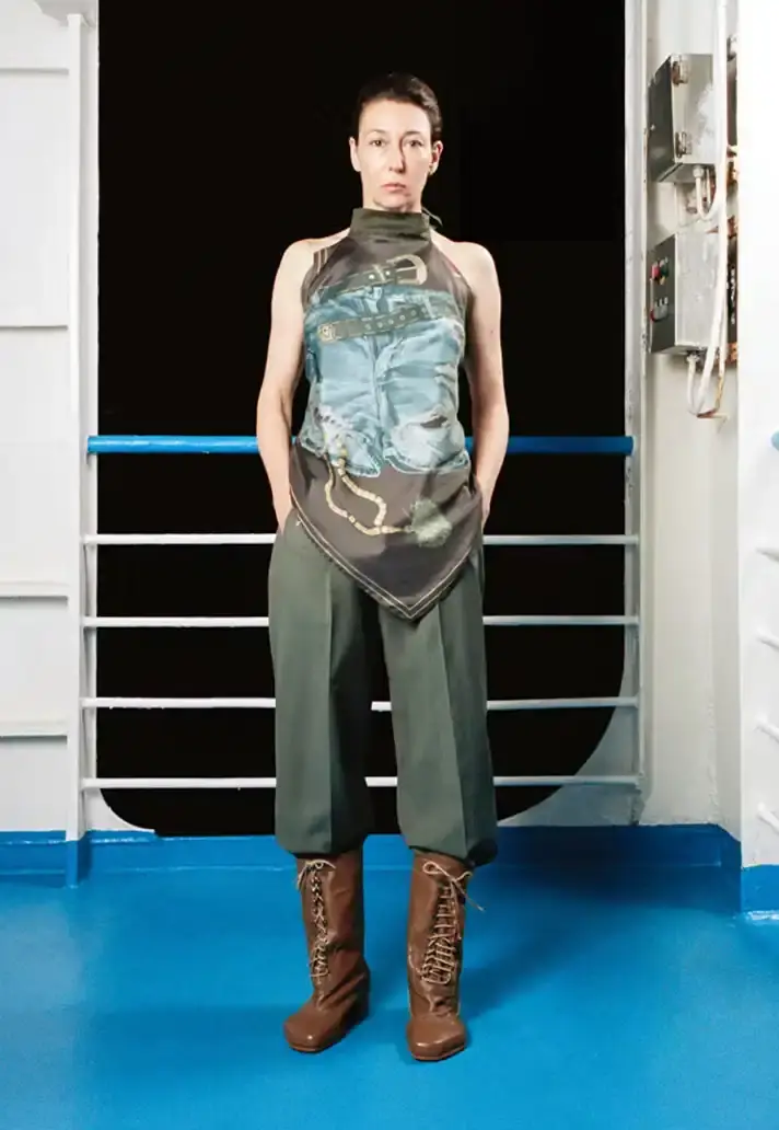 MAGLIANO SHOWS SS26 COLLECTION VIA FERRY FILM image about Italian designer Luca Magliano's Spring/Summer 2026 menswear collection, presented as a film aboard a ferry during Milan Fashion Week. The collection features camping and nomadic influences, with repurposed materials, loose silhouettes, and collaborative footwear including Beja soccer sneakers and 1900s-inspired boots. Shoot by Leonardo Scotti. (image 13 of 16)