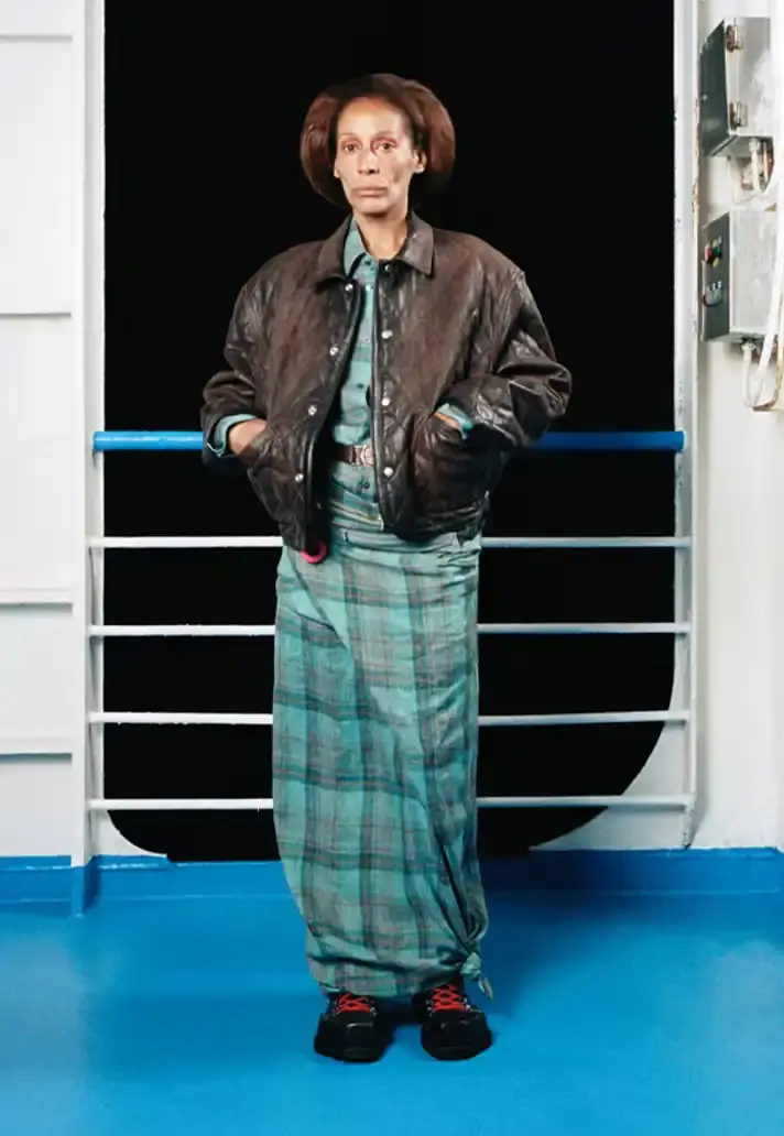 MAGLIANO SHOWS SS26 COLLECTION VIA FERRY FILM image about Italian designer Luca Magliano's Spring/Summer 2026 menswear collection, presented as a film aboard a ferry during Milan Fashion Week. The collection features camping and nomadic influences, with repurposed materials, loose silhouettes, and collaborative footwear including Beja soccer sneakers and 1900s-inspired boots. Shoot by Leonardo Scotti. (image 2 of 16)