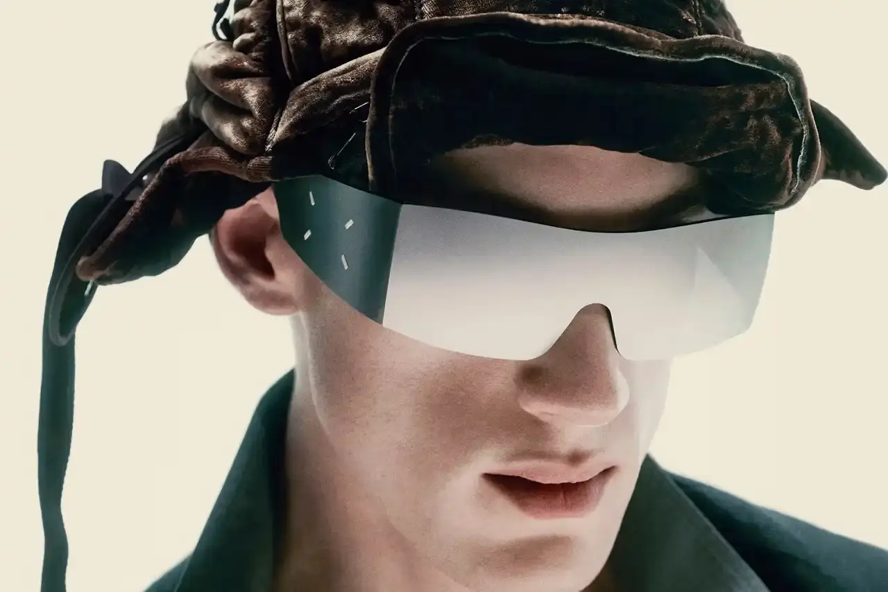 Maison Margiela/Gentle Monster Maison Margiela and Gentle Monster collaborative eyewear collection featuring avant-garde frames with cable temple details and distinctive metallic finishes. The sunglasses showcase the signature Margiela white stitch motif alongside cybercore-inspired design elements.