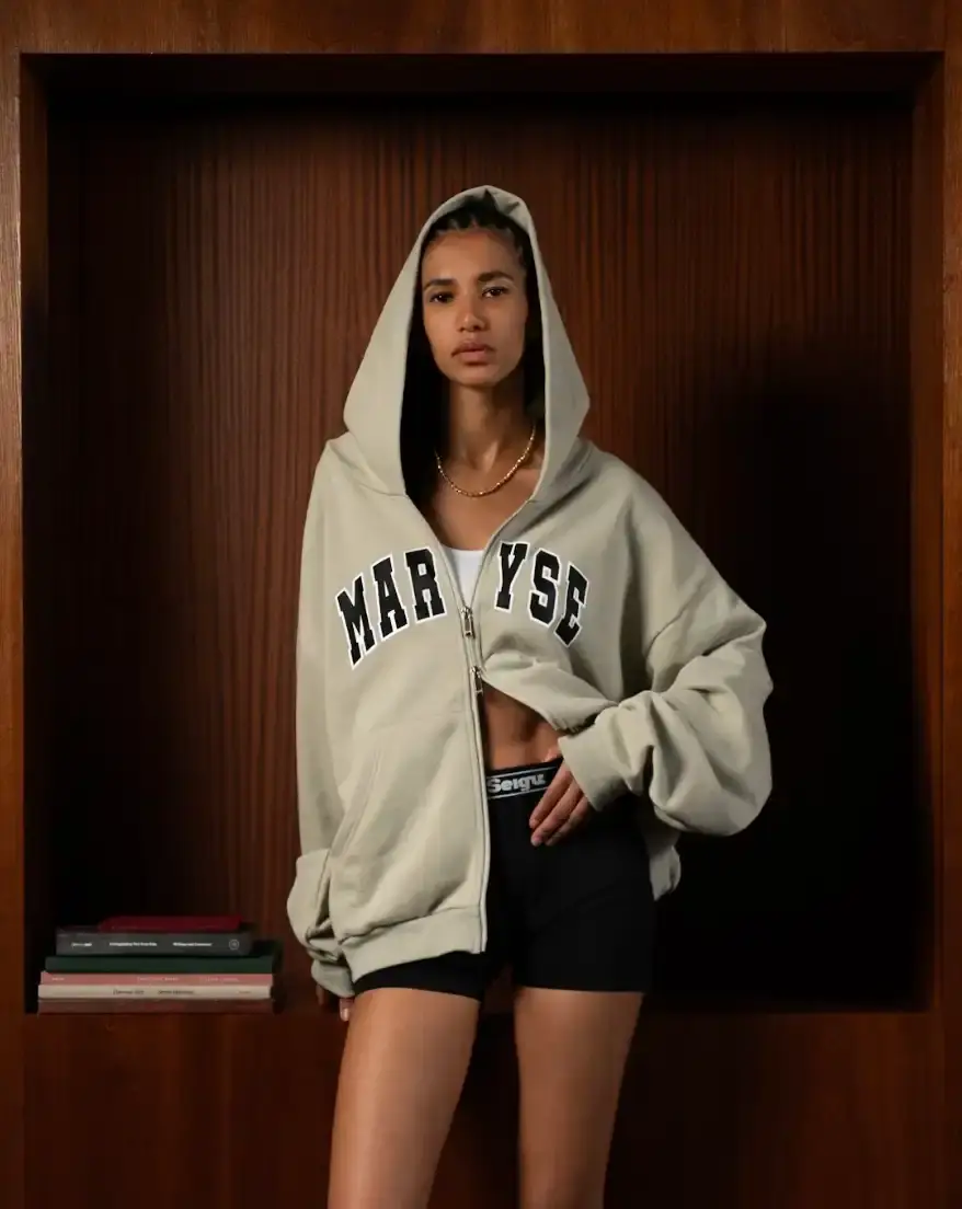 MARYSE SEIGU HONORS OLYMPIC PIONEER IN NEW COLLECTION image about the launch of Maryse Seigu's third fashion collection "CANGUIO S/S 25," which pays tribute to Marlene Canguio, the first woman from Guadeloupe to compete in the Olympic Games. The piece discusses the 13-item athletic-inspired collection that combines Caribbean cultural heritage with contemporary urban fashion, key pieces named after notable Afro-Caribbean athletes, and details about the brand's visual storytelling approach. The article includes information about a launch event in New York on May 23, 2025, and online availability starting May 29, 2025.