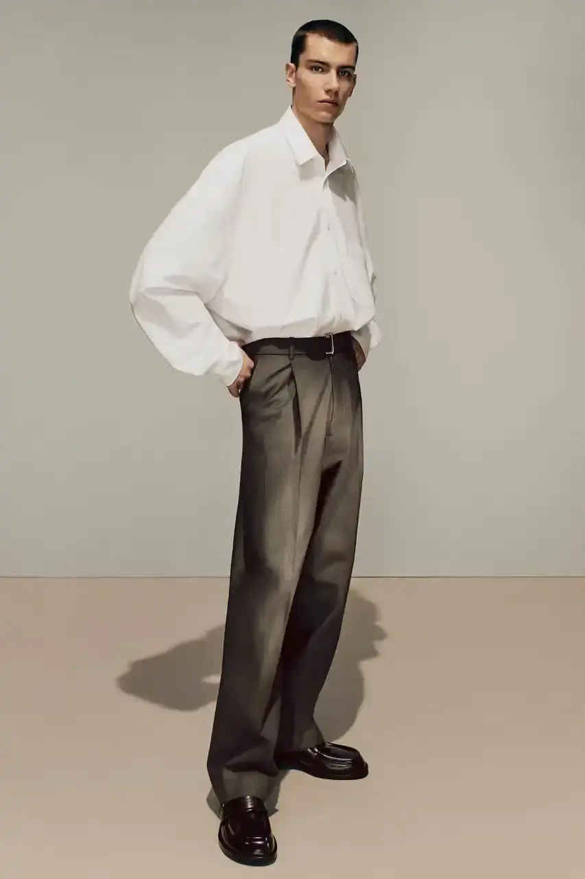 Acne Studios Male model wearing a gray tweed jacket over pink athletic tank top, paired with blue jeans and heart-shaped Acne Studios belt buckle (image 9 of 24)