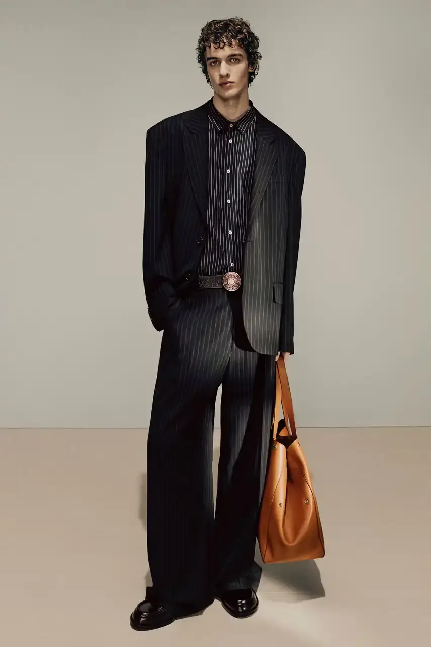Acne Studios Male model wearing a gray tweed jacket over pink athletic tank top, paired with blue jeans and heart-shaped Acne Studios belt buckle (image 5 of 24)