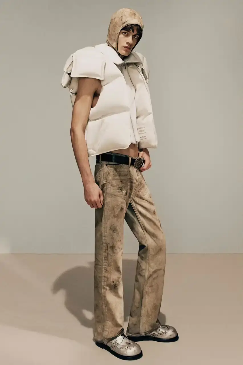 Acne Studios Model wearing layered sleeveless logo t-shirt over gray hoodie with cut-off sweatpants and compression shorts