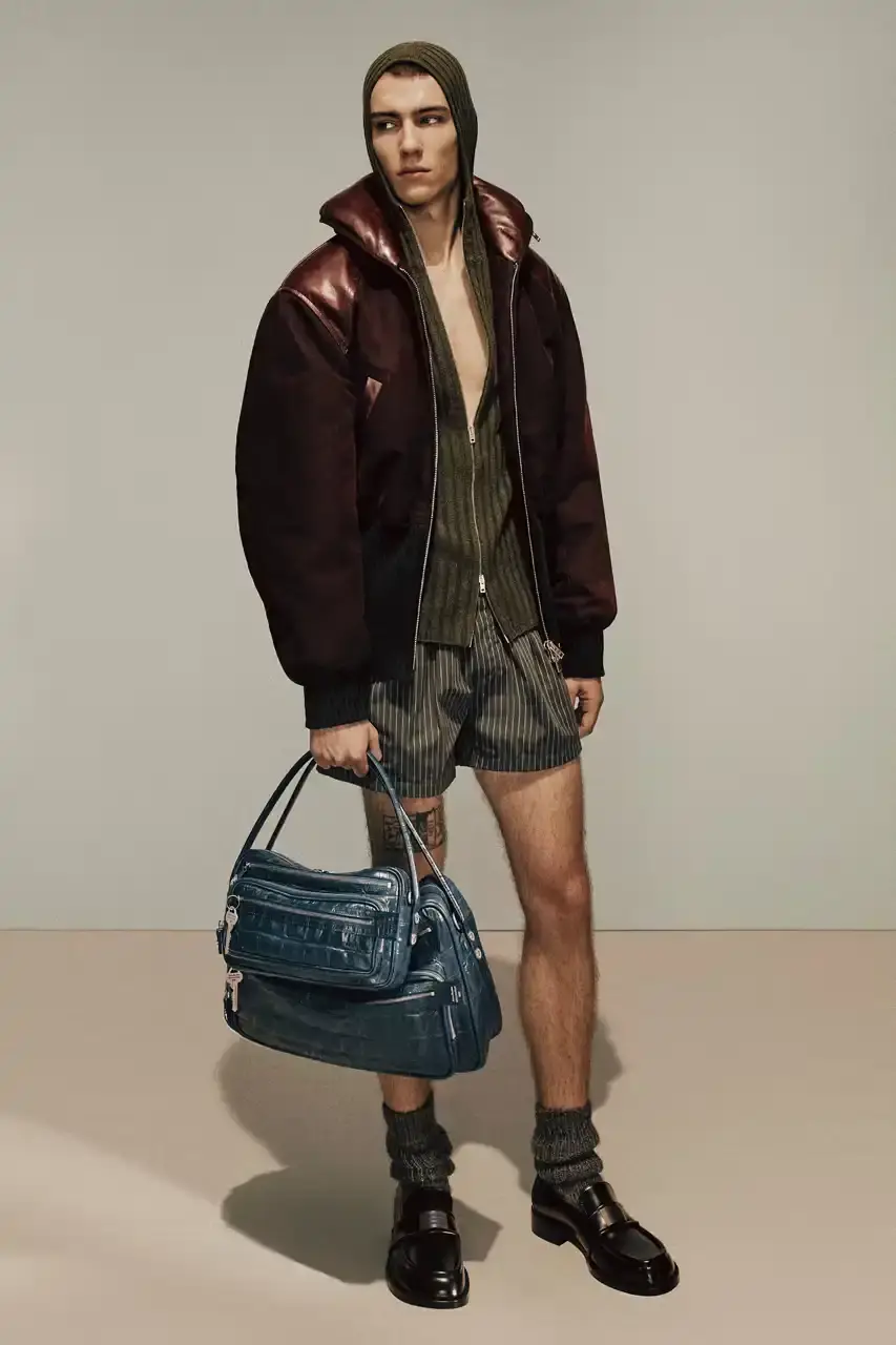 Acne Studios Model in Chanel-inspired tweed jacket styled with pink gym tank, jeans, and boots, carrying a large leather handbag