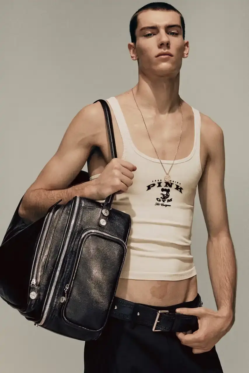 Acne Studios Male model wearing a gray tweed jacket over pink athletic tank top, paired with blue jeans and heart-shaped Acne Studios belt buckle (image 3 of 24)