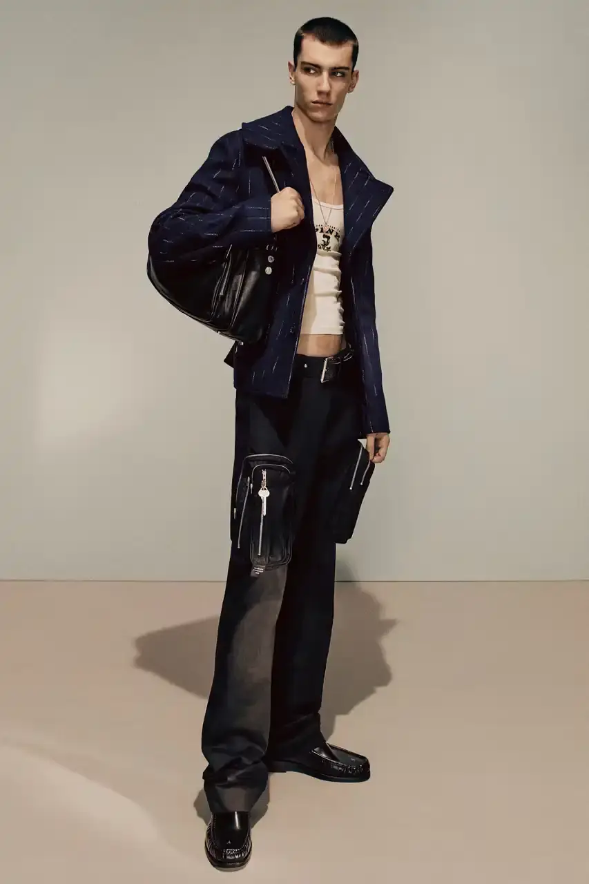 Acne Studios Male model wearing a gray tweed jacket over pink athletic tank top, paired with blue jeans and heart-shaped Acne Studios belt buckle (image 7 of 24)