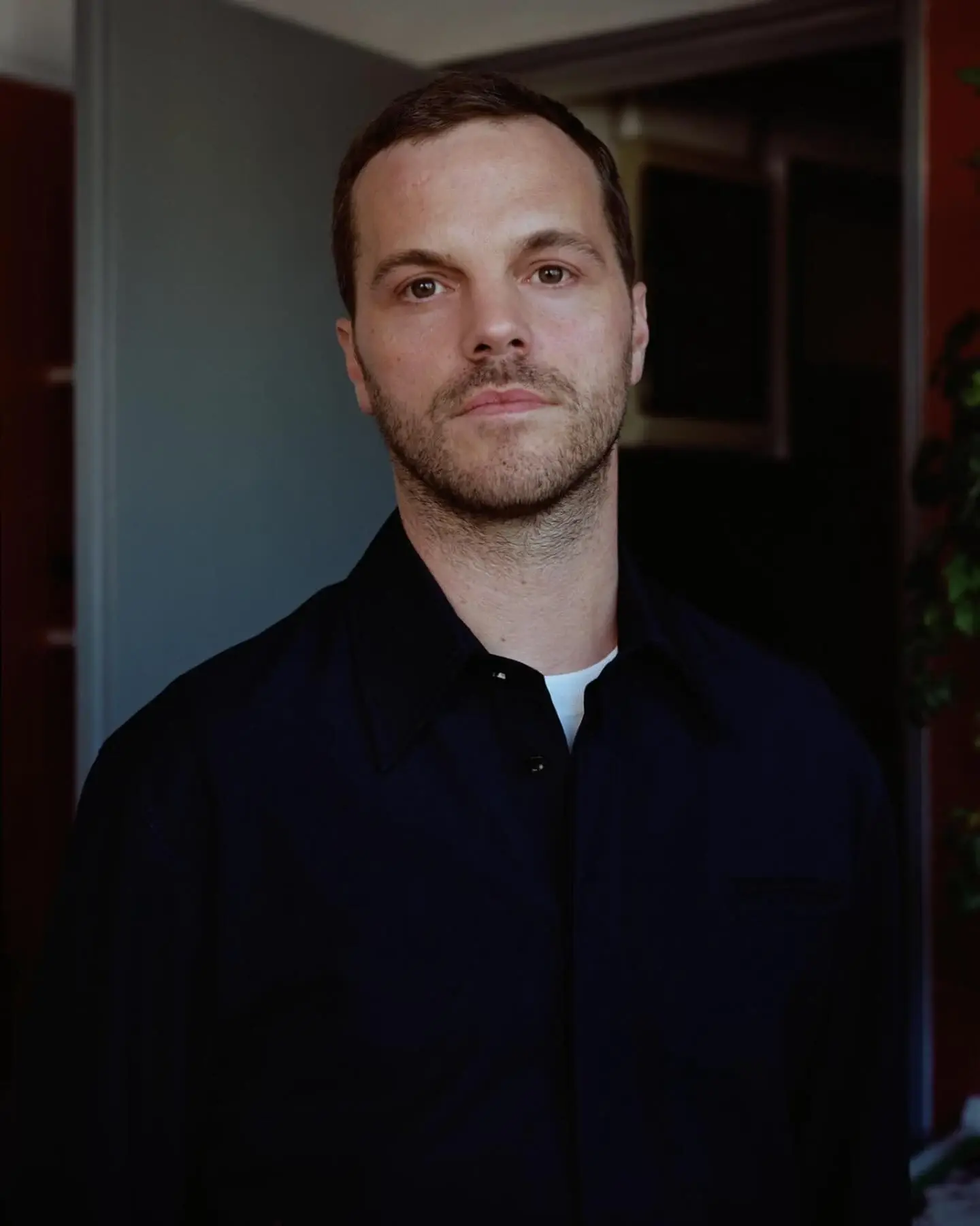A professional headshot of Matthieu Blazy, a young white male designer wearing a dark suit, looking directly at the camera with a serious, professional expression. The image represents his new role as Chanel's creative director, symbolizing the transition of creative leadership in the fashion industry.