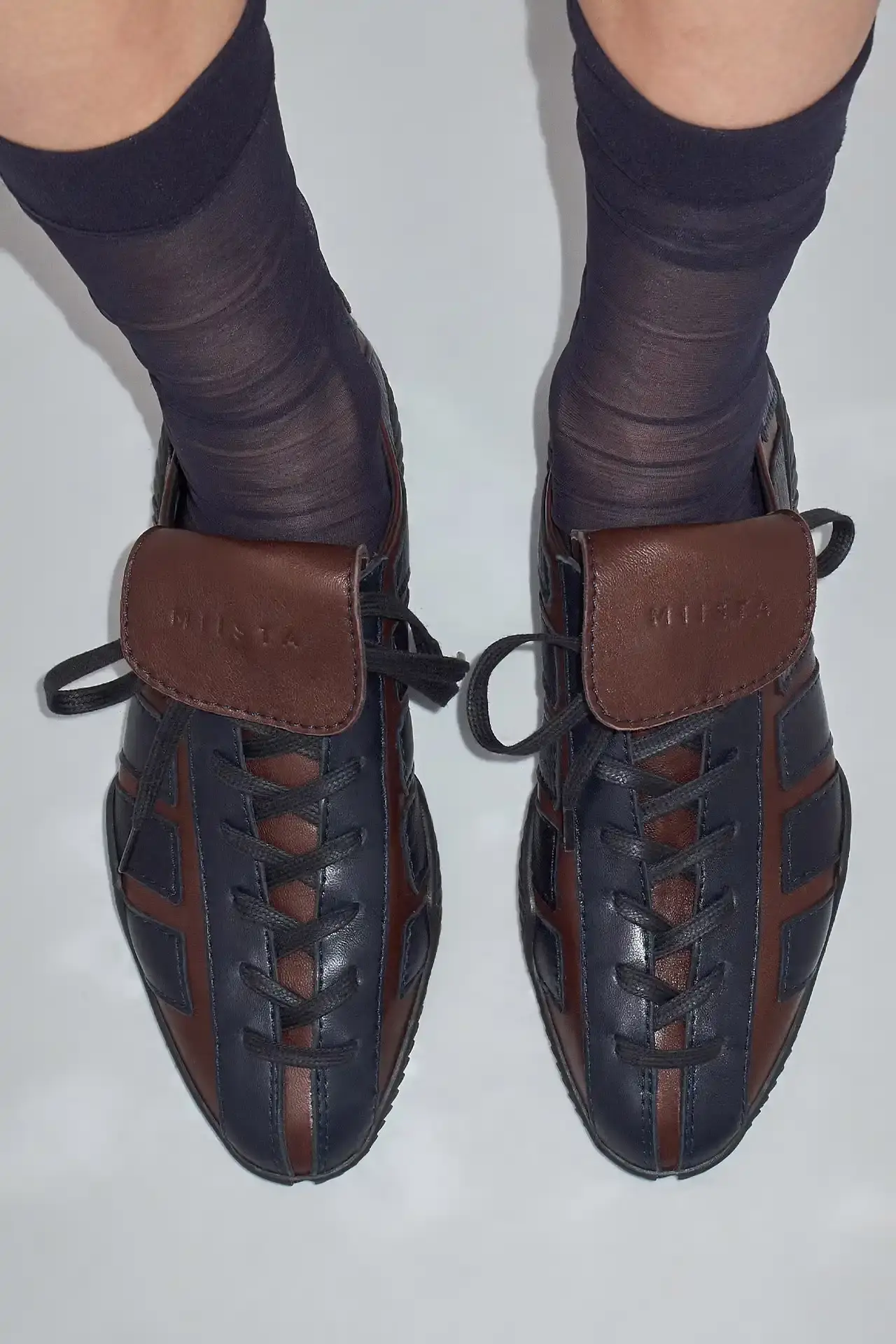 MIISTA'S NIKOLETTA: A THROWBACK TO 80S ATHLETIC FOOTWEAR Photo about Miista's new Nikoletta sneaker. Describes the low-profile design inspired by 1980s athletic footwear, construction details including goat leather and fold-over tongue, available colors (black, brown/navy, black/white), price ($415), and where to purchase. Includes quote from creative director Laura Villasenin about the brand's philosophy of continuous improvement and craftsmanship.