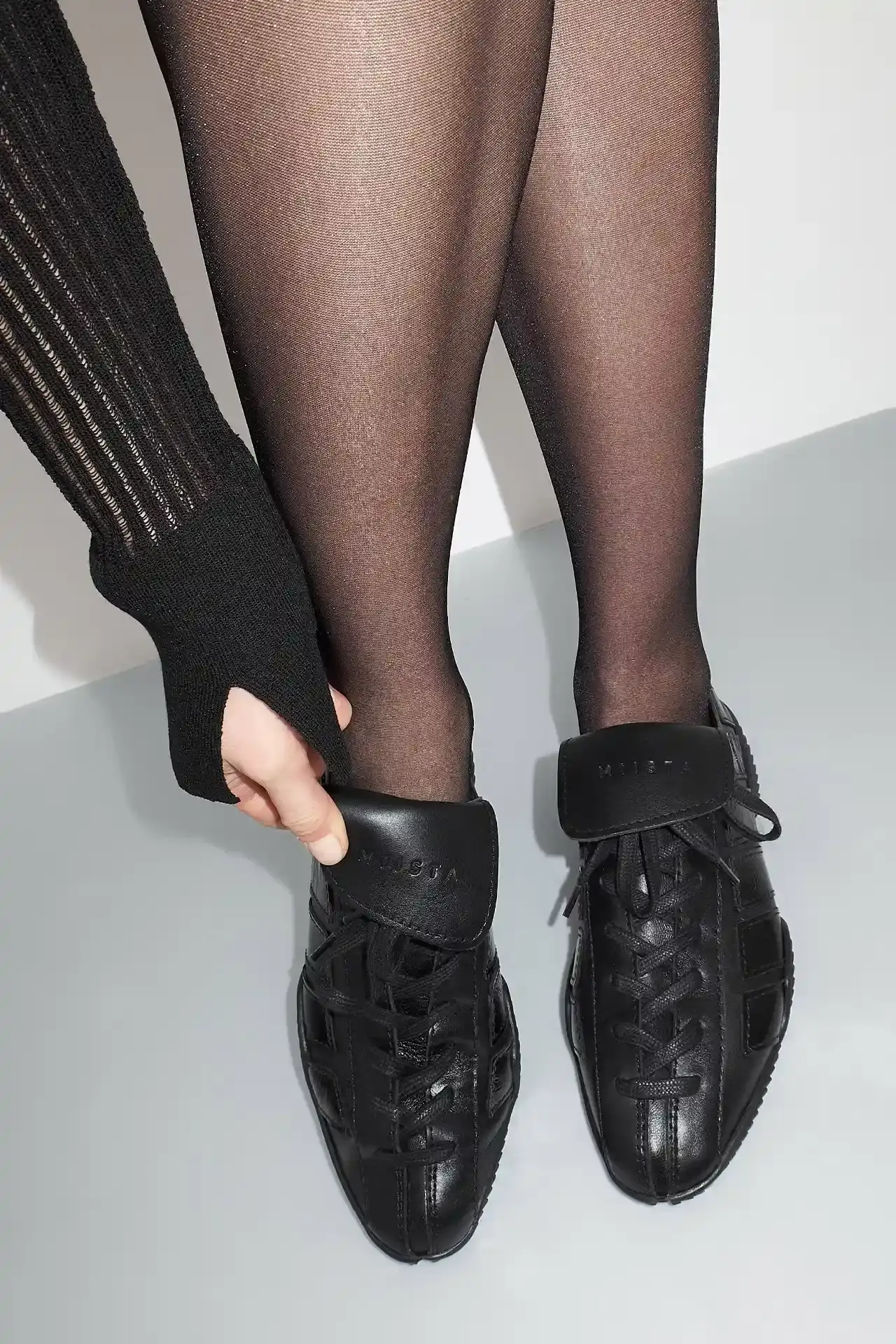 MIISTA'S NIKOLETTA: A THROWBACK TO 80S ATHLETIC FOOTWEAR Photo about Miista's new Nikoletta sneaker. Describes the low-profile design inspired by 1980s athletic footwear, construction details including goat leather and fold-over tongue, available colors (black, brown/navy, black/white), price ($415), and where to purchase. Includes quote from creative director Laura Villasenin about the brand's philosophy of continuous improvement and craftsmanship. (image 2 of 4)