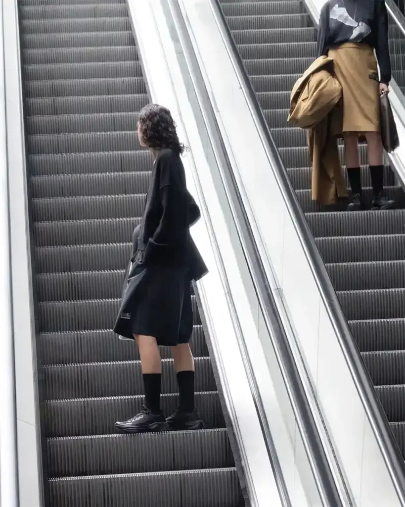 MM6 MAISON MARGIELA AND SALOMON DEBUT NEW JOINT COLLECTION FOR SPRING/SUMMER 2025 photo of the Spring/Summer 2025 collaboration between fashion brand MM6 Maison Margiela and athletic brand Salomon. It describes their unisex collection that combines experimental design with technical sportswear functionality. The collection includes running-inspired garments with technical materials and distinctive proportions, plus footwear like the Spectur 2 running shoe in black and sage green, and new colorways of the XT-4 Mule. The collection will be released in two drops on April 17 and May 8, available through both brands' websites and select retailers. (image 5 of 7)