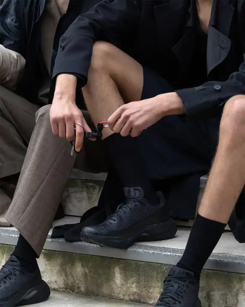 MM6 MAISON MARGIELA AND SALOMON DEBUT NEW JOINT COLLECTION FOR SPRING/SUMMER 2025 photo of the Spring/Summer 2025 collaboration between fashion brand MM6 Maison Margiela and athletic brand Salomon. It describes their unisex collection that combines experimental design with technical sportswear functionality. The collection includes running-inspired garments with technical materials and distinctive proportions, plus footwear like the Spectur 2 running shoe in black and sage green, and new colorways of the XT-4 Mule. The collection will be released in two drops on April 17 and May 8, available through both brands' websites and select retailers. (image 3 of 7)