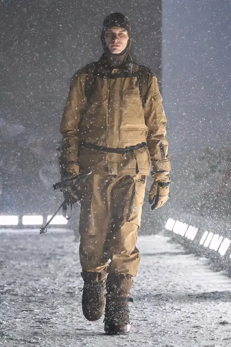 Moncler Moncler's Fall/Winter 2025 Grenoble collection showcase held at Courchevel Altiport in the French Alps. It details how the runway show transformed Europe's highest airport into a fashion venue at 2,008 meters above sea level. The article outlines the collection's 140 looks that blend urban style with mountain functionality, featuring innovative materials like denim and canvas alongside traditional winter textiles. It mentions the craftsmanship details including embroidery and intarsia patterns on ski suits. The article also notes celebrity attendees and a special snowboard collaboration with Shaun White's WHITESPACE brand. The content is organized in paragraphs describing the event setting, collection details, and notable highlights (image 5 of 22)