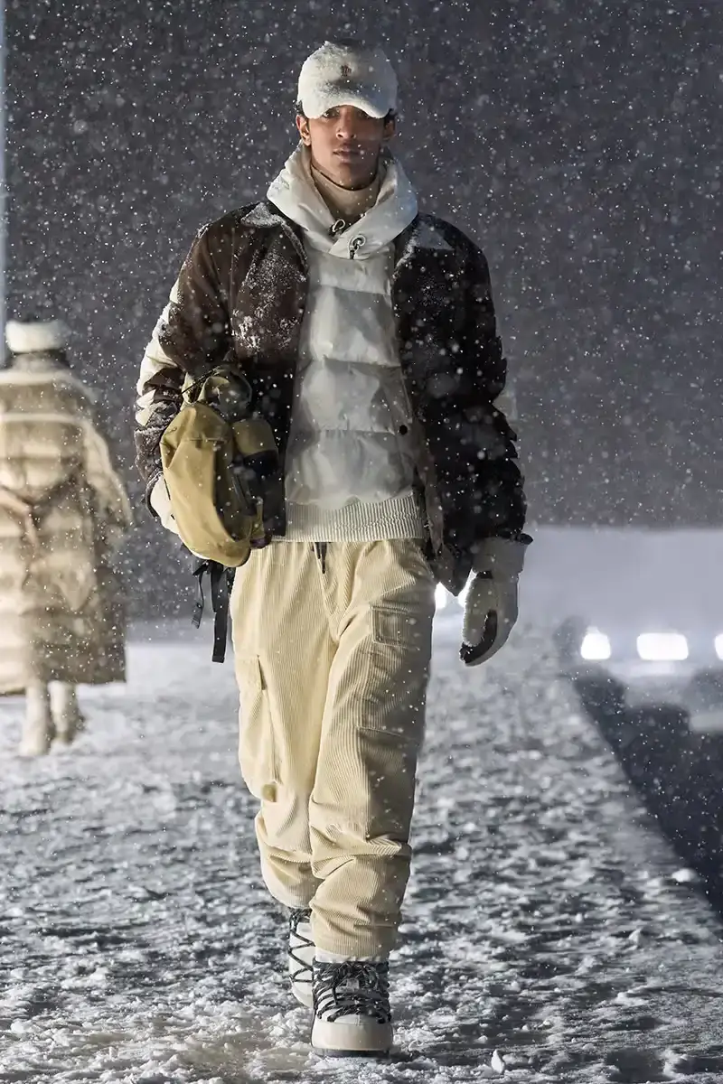 Moncler Moncler's Fall/Winter 2025 Grenoble collection showcase held at Courchevel Altiport in the French Alps. It details how the runway show transformed Europe's highest airport into a fashion venue at 2,008 meters above sea level. The article outlines the collection's 140 looks that blend urban style with mountain functionality, featuring innovative materials like denim and canvas alongside traditional winter textiles. It mentions the craftsmanship details including embroidery and intarsia patterns on ski suits. The article also notes celebrity attendees and a special snowboard collaboration with Shaun White's WHITESPACE brand. The content is organized in paragraphs describing the event setting, collection details, and notable highlights (image 9 of 22)