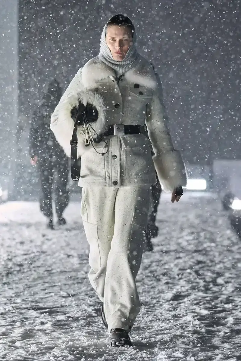 Moncler Moncler's Fall/Winter 2025 Grenoble collection showcase held at Courchevel Altiport in the French Alps. It details how the runway show transformed Europe's highest airport into a fashion venue at 2,008 meters above sea level. The article outlines the collection's 140 looks that blend urban style with mountain functionality, featuring innovative materials like denim and canvas alongside traditional winter textiles. It mentions the craftsmanship details including embroidery and intarsia patterns on ski suits. The article also notes celebrity attendees and a special snowboard collaboration with Shaun White's WHITESPACE brand. The content is organized in paragraphs describing the event setting, collection details, and notable highlights (image 3 of 22)